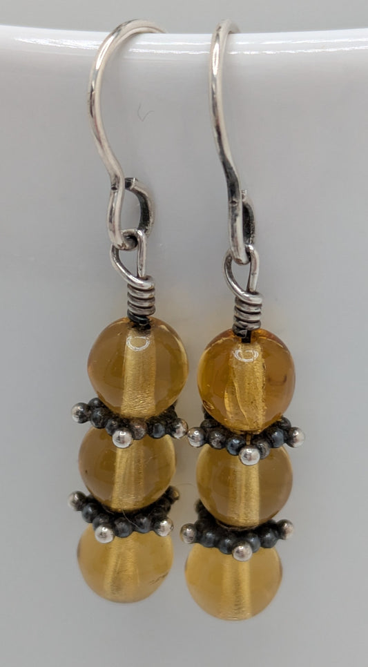 Pair of earrings with yellow beads and silver accents on a white background