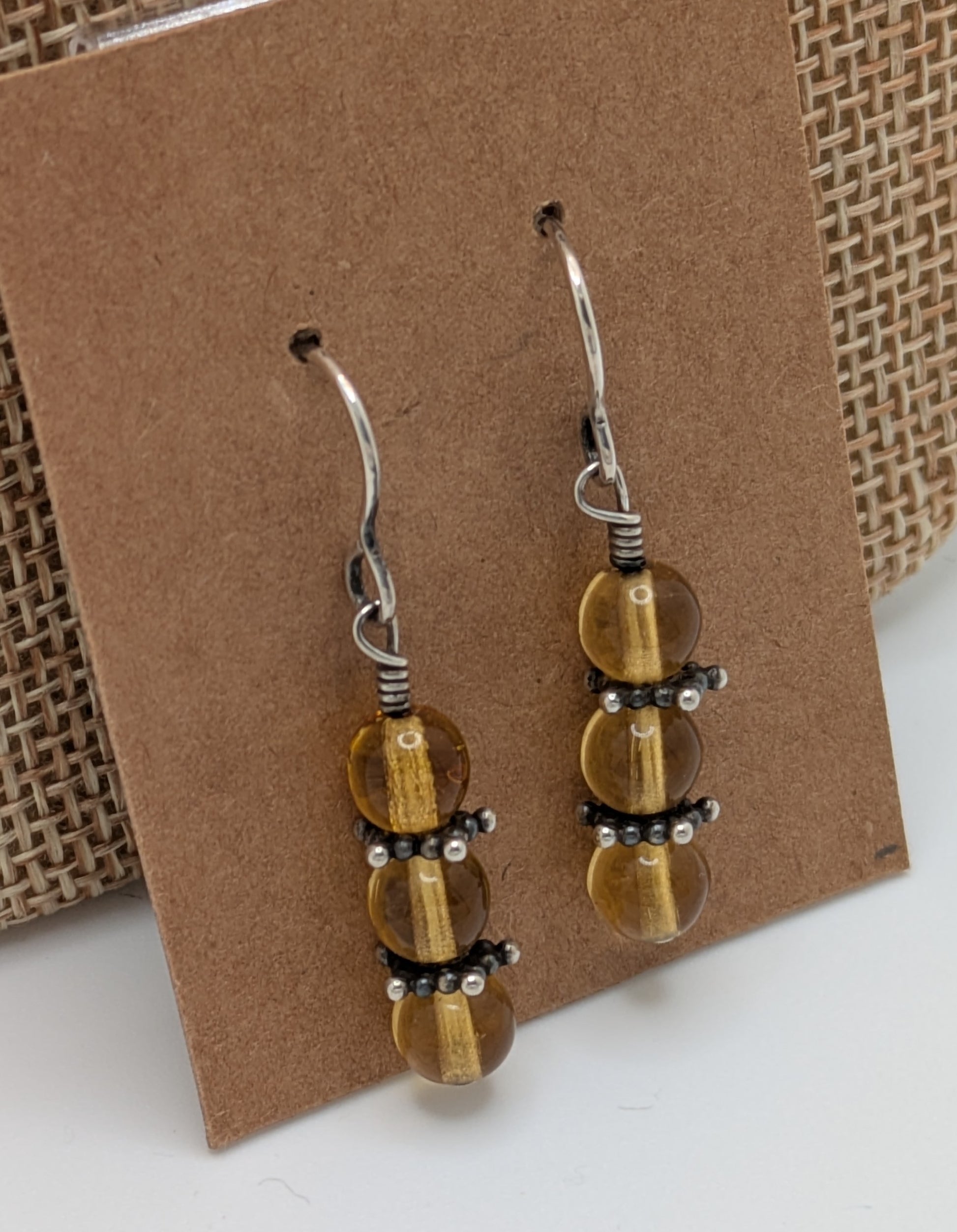 Pair of beaded earrings on a brown card with a textured background