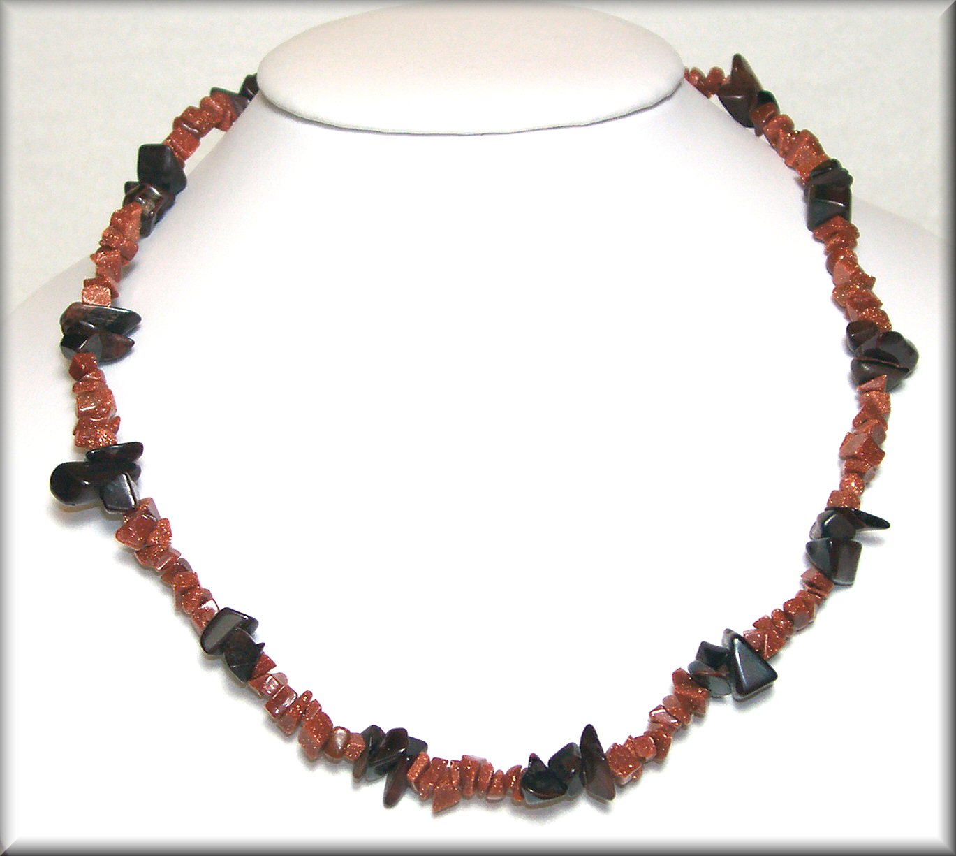 A red goldstone and jasper beaded necklace displayed on a mannequin bust.