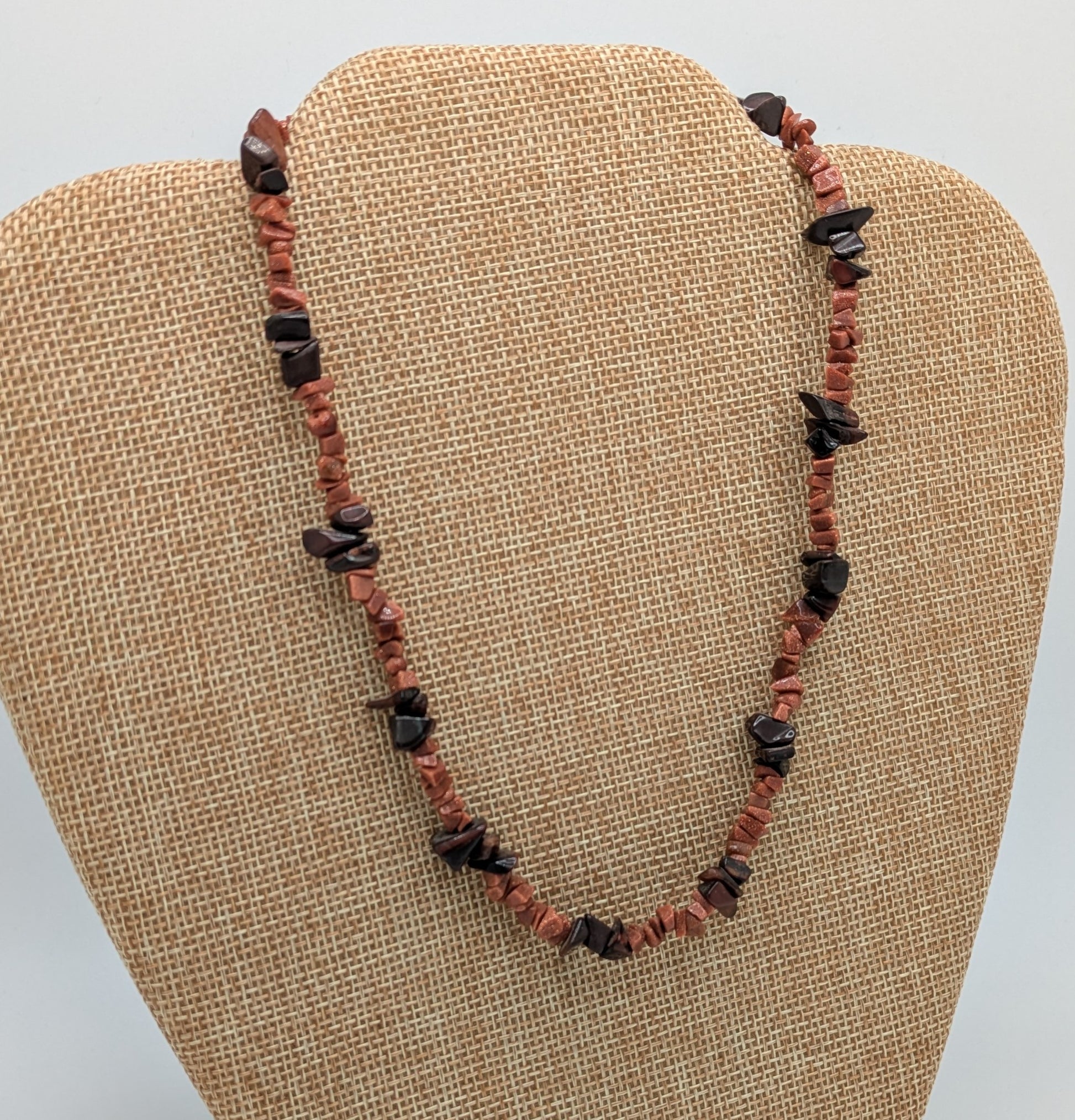 Necklace with red and black beads on a beige display stand
